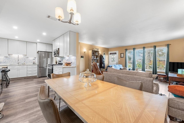 dining room featuring light wood-type flooring, visible vents, recessed lighting, and an inviting chandelier