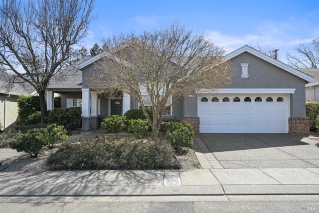 view of front of home with a garage, stucco siding, driveway, and brick siding