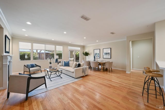 living room featuring light wood-style floors, baseboards, visible vents, and a wealth of natural light