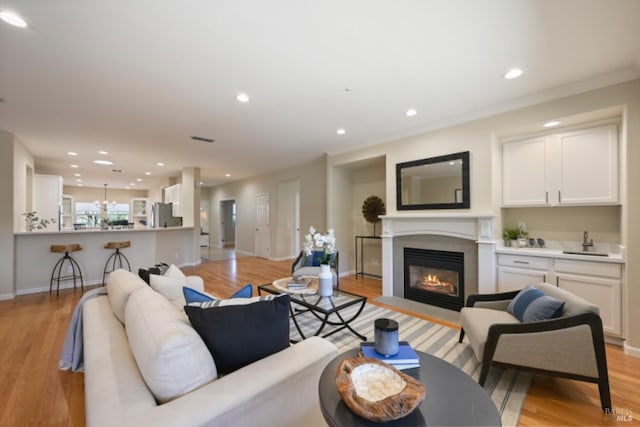 living area featuring a fireplace with flush hearth, recessed lighting, light wood-style flooring, and baseboards