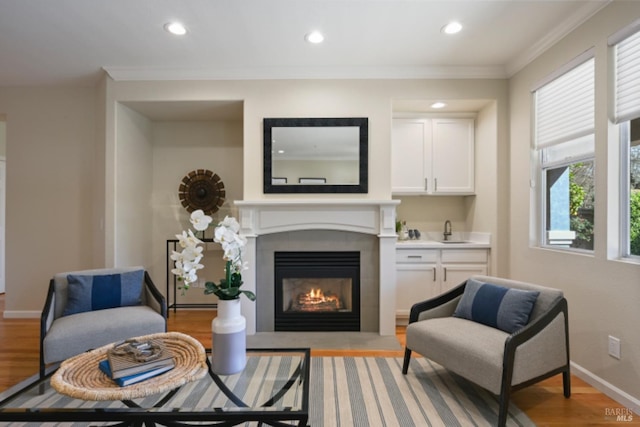 sitting room with light wood-style flooring, baseboards, crown molding, and recessed lighting