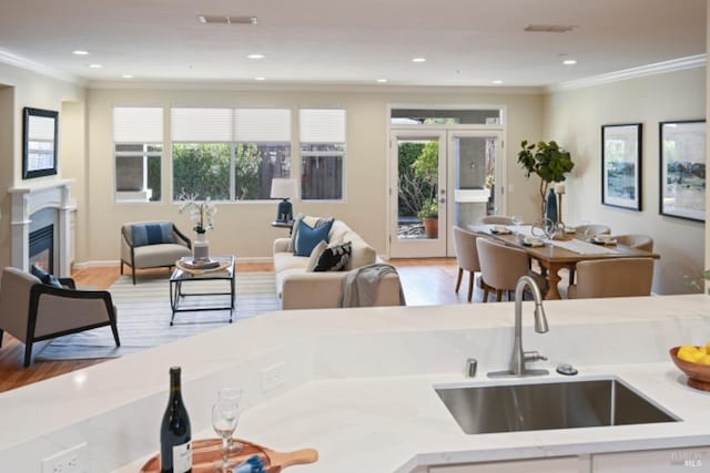 kitchen with ornamental molding, open floor plan, visible vents, and a sink