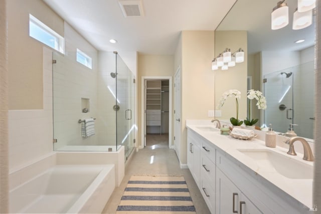 bathroom featuring a shower stall, a spacious closet, visible vents, and a sink