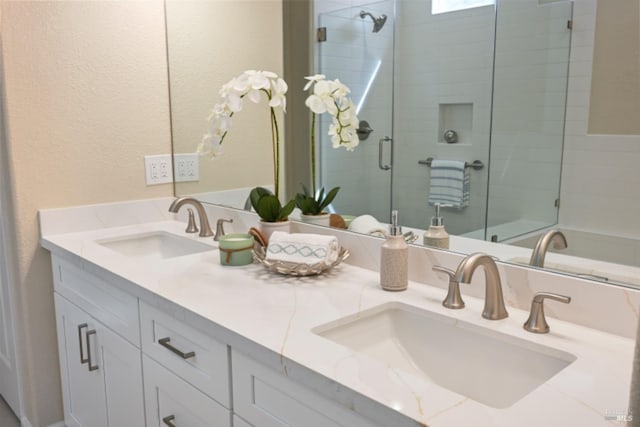 full bath with double vanity, a stall shower, and a sink