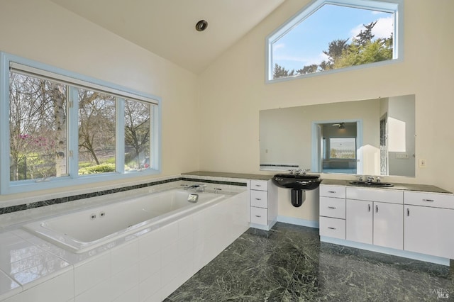 full bathroom featuring marble finish floor, plenty of natural light, high vaulted ceiling, and a garden tub