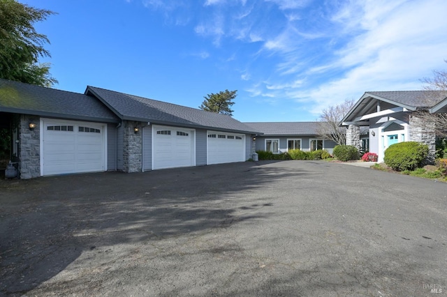 view of front of home with aphalt driveway, stone siding, and an attached garage