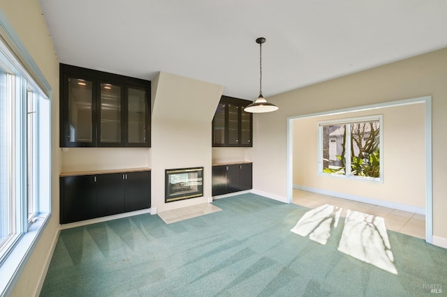 unfurnished living room with baseboards, carpet floors, a fireplace with flush hearth, and a healthy amount of sunlight