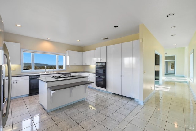 kitchen with light tile patterned flooring, a kitchen island, a sink, white cabinetry, and black appliances