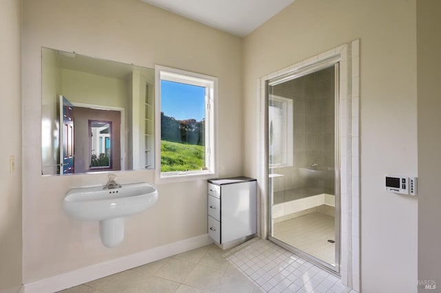 full bath with a sink, a stall shower, tile patterned flooring, and baseboards