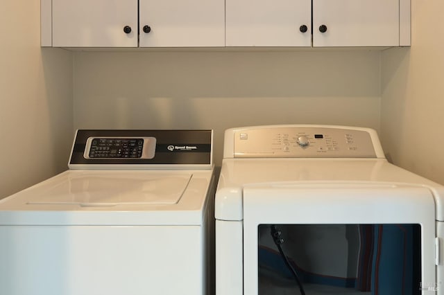 clothes washing area featuring cabinet space and separate washer and dryer