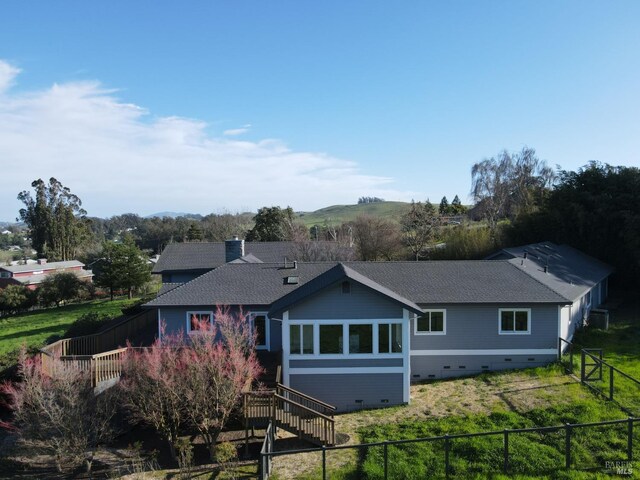 rear view of property with roof with shingles, a chimney, crawl space, fence, and stairs