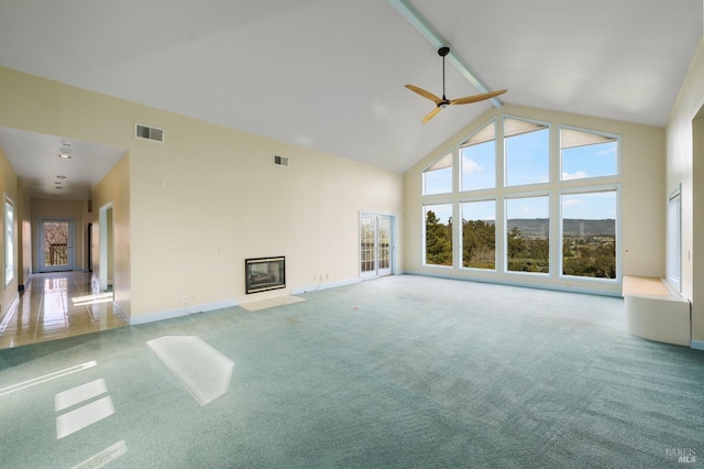 unfurnished living room featuring high vaulted ceiling, a wealth of natural light, a fireplace with flush hearth, and visible vents