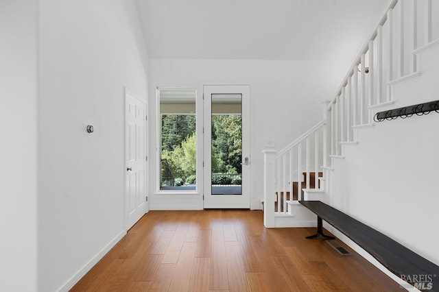 entryway featuring visible vents, baseboards, wood finished floors, and stairs