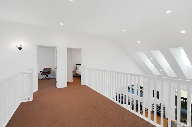 hall with carpet, vaulted ceiling with skylight, recessed lighting, and a wainscoted wall