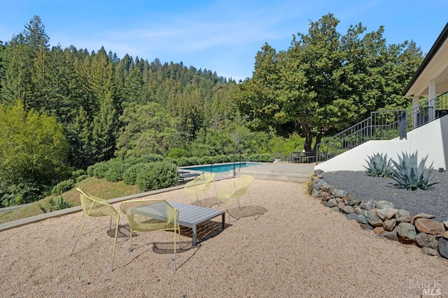 exterior space with a wooded view, a patio area, and an outdoor pool