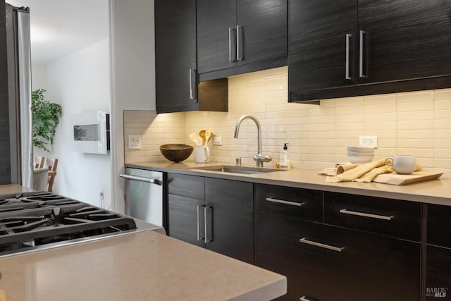 kitchen with light countertops, dark cabinetry, backsplash, and a sink