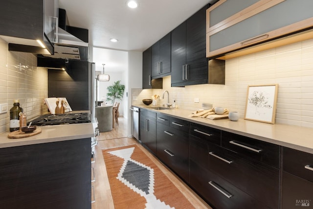 kitchen featuring tasteful backsplash, light countertops, a sink, dark cabinets, and dishwasher