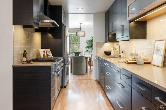 kitchen featuring a sink, light wood-style floors, light countertops, appliances with stainless steel finishes, and tasteful backsplash