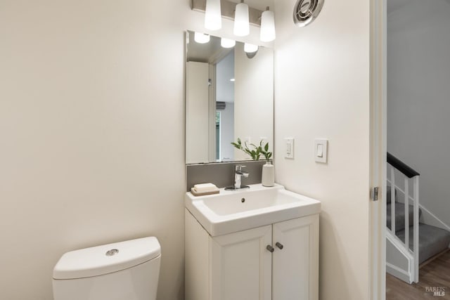 half bath with wood finished floors, vanity, and toilet