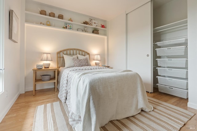 bedroom with light wood-style floors, baseboards, and a closet