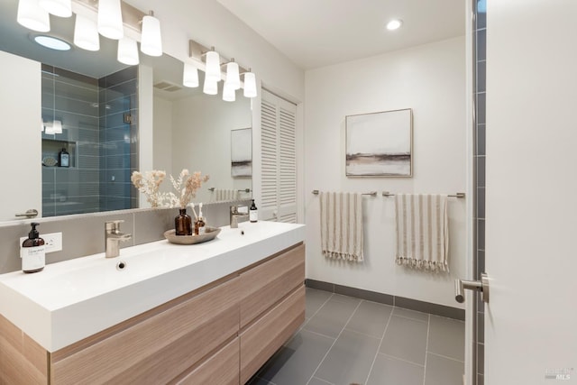 full bath featuring double vanity, baseboards, tile patterned floors, a shower stall, and a sink