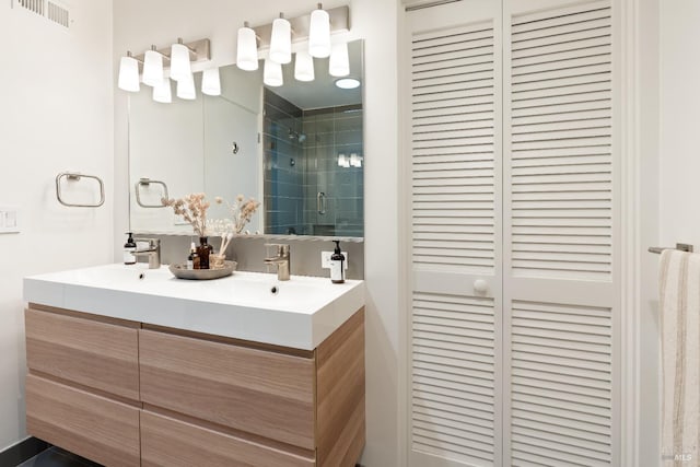 full bathroom featuring double vanity, a stall shower, a closet, visible vents, and a sink