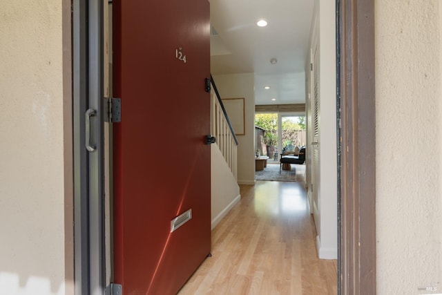 corridor featuring light wood-type flooring, stairs, baseboards, and recessed lighting