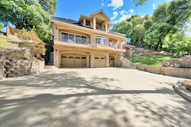 view of front facade with stairway, concrete driveway, stucco siding, a balcony, and a garage