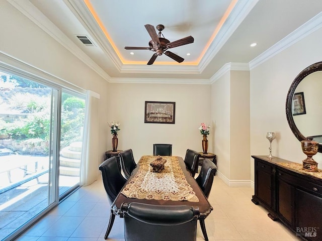 dining area featuring visible vents, a tray ceiling, crown molding, baseboards, and ceiling fan