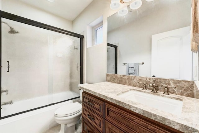 full bath featuring toilet, vanity, and shower / bath combination with glass door