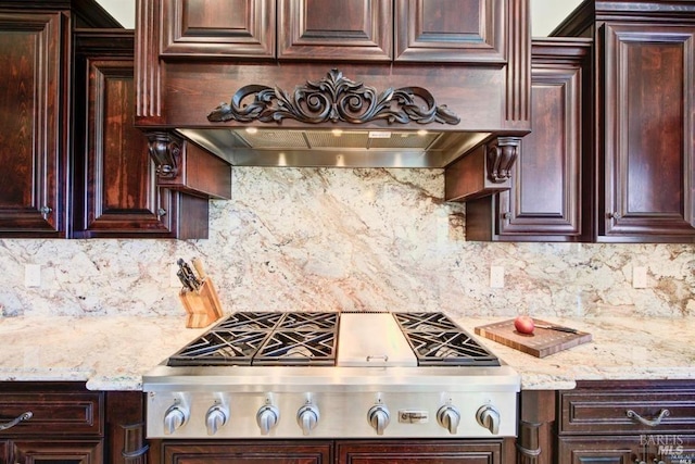 kitchen featuring dark brown cabinetry, stainless steel gas stovetop, decorative backsplash, and light stone countertops