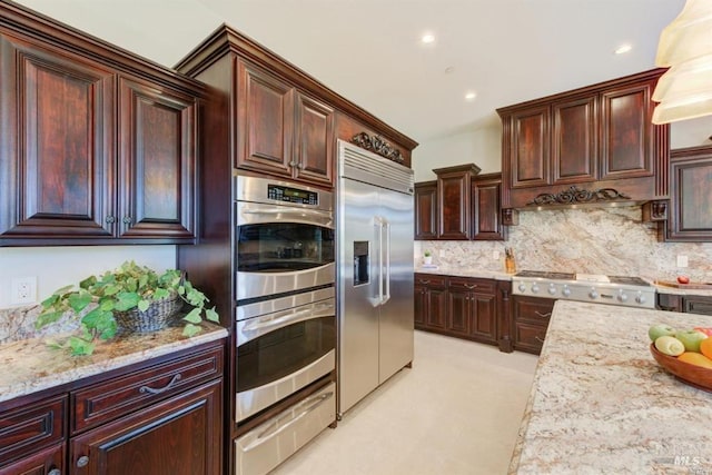 kitchen with a warming drawer, stainless steel appliances, light stone counters, and backsplash