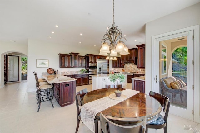 dining room with a chandelier, light tile patterned floors, recessed lighting, and arched walkways