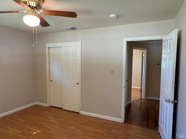 unfurnished bedroom featuring a closet, visible vents, baseboards, and wood finished floors