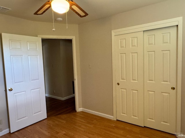 unfurnished bedroom featuring baseboards, a closet, visible vents, and wood finished floors