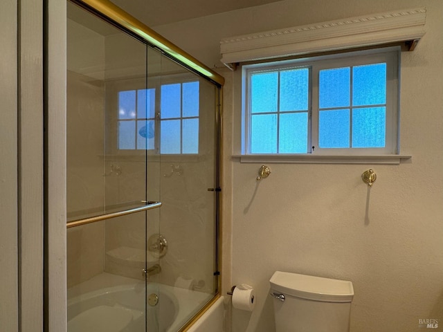 bathroom featuring enclosed tub / shower combo and toilet