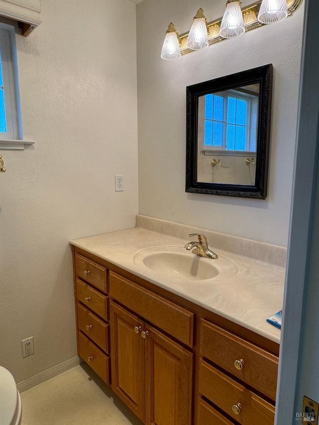 bathroom with toilet, baseboards, and vanity