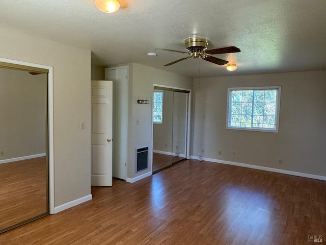 unfurnished bedroom with a textured ceiling, baseboards, and wood finished floors