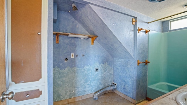 bathroom featuring tile patterned flooring, vaulted ceiling, a textured ceiling, and a sink