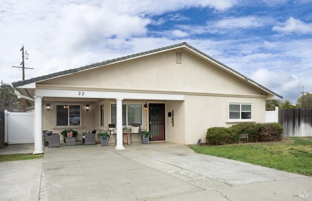 view of front of property with fence, a porch, and stucco siding