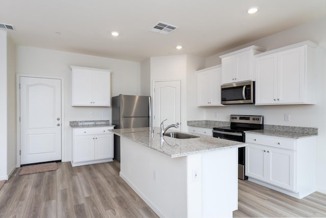 kitchen featuring stainless steel appliances, visible vents, white cabinets, a sink, and an island with sink