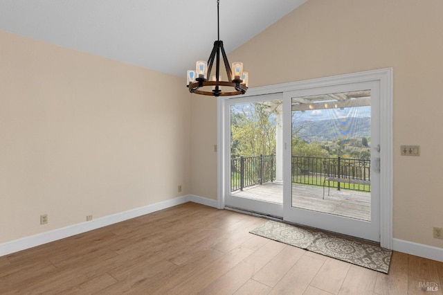 interior space with lofted ceiling, an inviting chandelier, baseboards, and wood finished floors