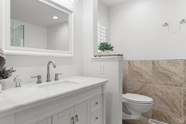 bathroom with toilet, tile walls, and vanity