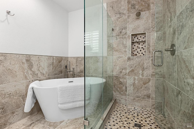 bathroom with tile walls, a soaking tub, and a shower stall