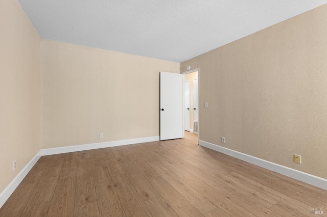 unfurnished room with baseboards and hardwood / wood-style floors