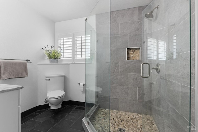 bathroom with toilet, vanity, baseboards, a shower stall, and tile patterned floors