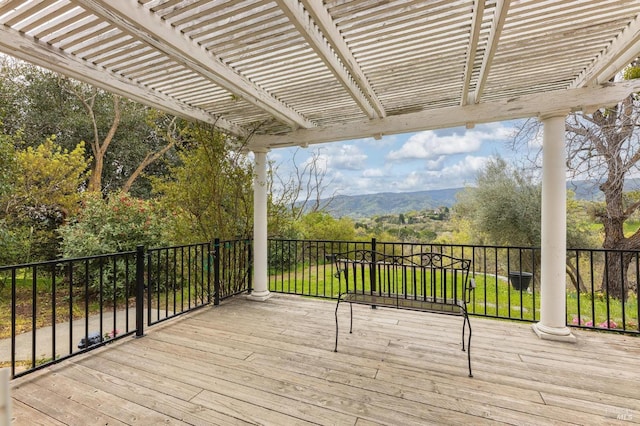 deck featuring a mountain view, a pergola, and a yard