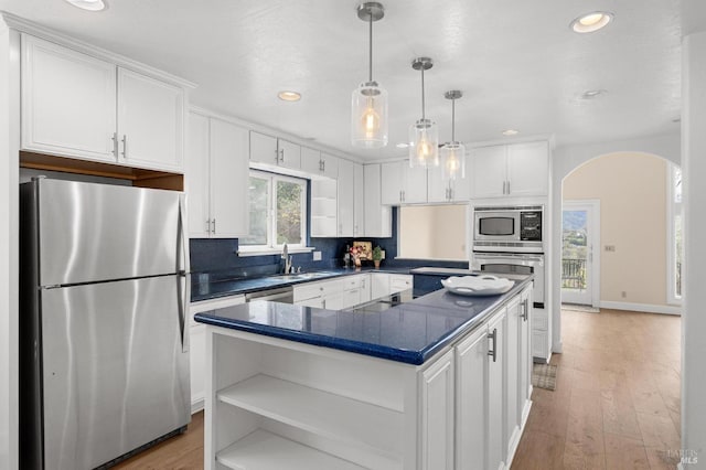 kitchen featuring arched walkways, dark countertops, appliances with stainless steel finishes, white cabinetry, and open shelves