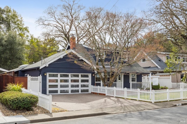 view of front of property featuring a fenced front yard, concrete driveway, a chimney, and a garage