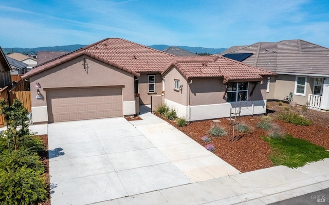 mediterranean / spanish-style home featuring a tiled roof, an attached garage, driveway, and stucco siding